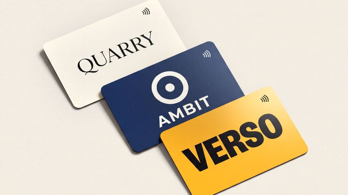 Three cards from three different companies fanned out on a pale studio surface — cobalt, coral and emerald matte PVC, each with its own logo centred and the contactless indicator in the corner